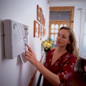 A woman pressing a button of a home security system.